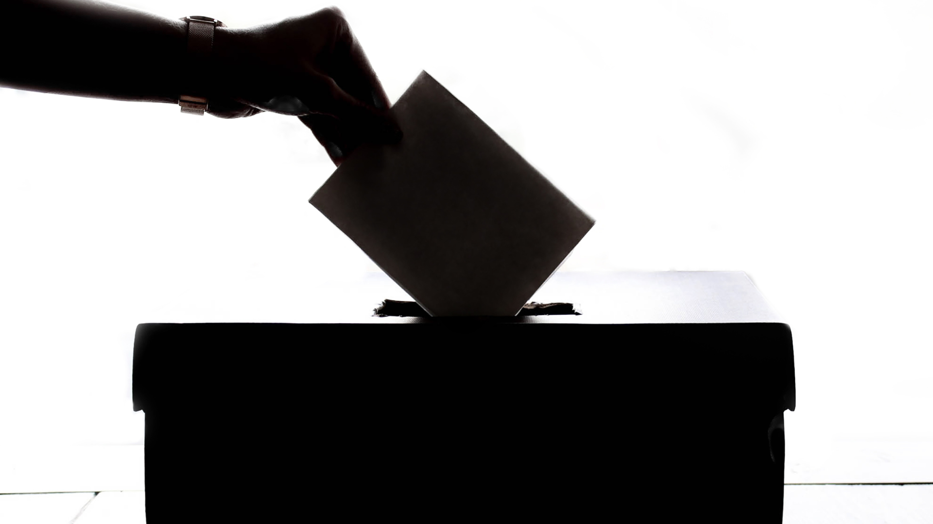 Silueta d'una mà dipositant un vot a una urna.